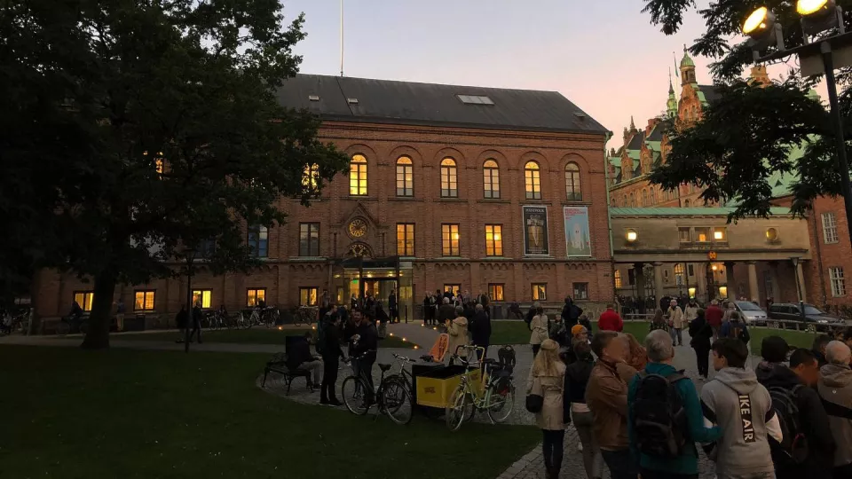 Historiska museet i solnedgång. Framför byggnaden står en stor samling människor.