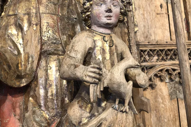 Foto på medeltida träskulptur som föreställer Jesus hållande i en fågel.