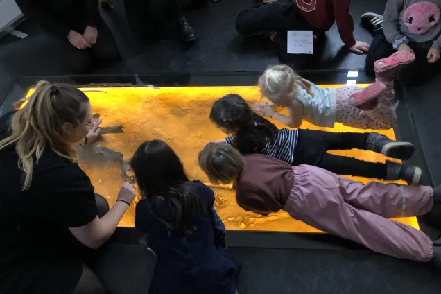 Museiguide som visar stenåldersgrav för skolbarn.