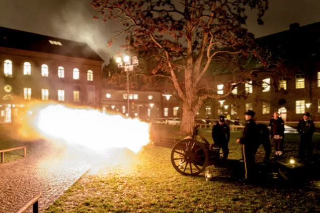 En kanon blir avfyrad framför historiska museet. Himlen är rökfylld och ur kanonen syns eld.