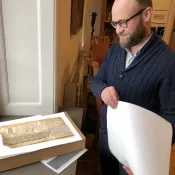 Foto på man som står och tittar på medeltida pappersmaterial.