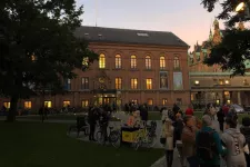 Historiska museet i solnedgång. Framför byggnaden står en stor samling människor.