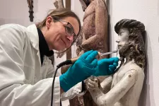 Foto: Konservatorn Nadine fäster färg på en medeltida skulptur.